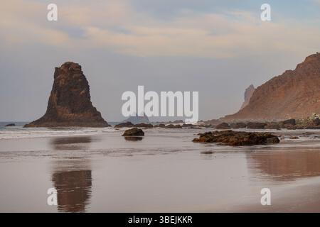 Moody Sonnenuntergang über Playa de Benijo, einem abgeschiedenen vulkanischen Strand im Anaga Rural Park, mit dramatischen Wellen, die gegen die zerklüftete Küste stürzen Stockfoto