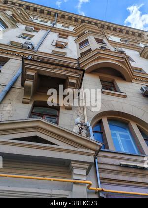 Nahaufnahme einer verwitterten Gebäudefassade mit sichtbaren Rissen und Klimaanlagen. Dieses Foto zeigt den Tribut der Urbanisierung an der Geschichte Stockfoto