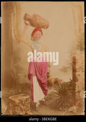 Dieses Studio-Porträt zeigt eine Frau mit Krügen, aufgenommen zwischen 1860 und 1900. Die Frau trägt traditionelle griechische Kleidung, die die kulturelle Kleidung der damaligen Zeit widerspiegelt. Das Foto wurde von einem unbekannten Fotografen in den 1800er Jahren aufgenommen Stockfoto