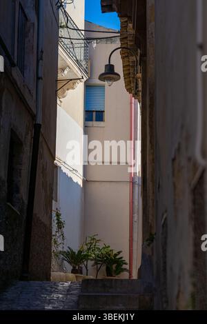 Eine enge Straße von Scicli, Sizilien, Italien, meist im Schatten. An einem sonnigen Wintertag ohne Menschen Stockfoto