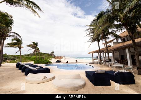 Luxuriöse Unterkünfte am Strand auf Cozumel Island, mit einem ruhigen Pool umgeben von Liegestühlen unter luftigen Palmen und Blick auf die Stockfoto