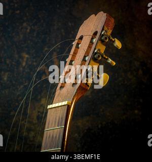 Eine klassische Gitarre ist prominent positioniert und zeigt ihr kompliziertes Holzdesign und gebrochene Saiten. Stockfoto