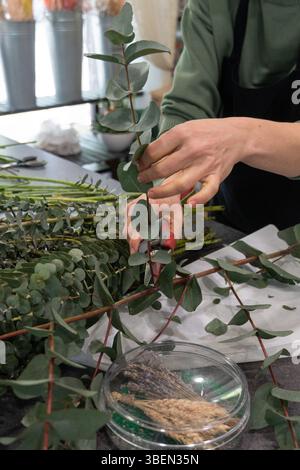 Ein Florist trimmt Eukalyptuszweige an einer Werkbank in einem Blumenladen Stockfoto