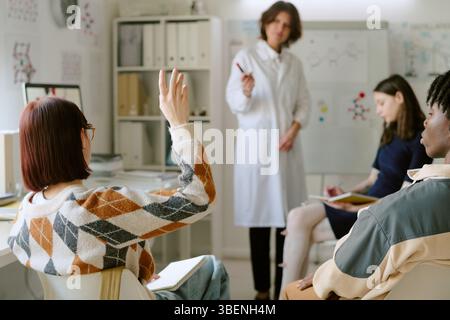 Schüler nehmen an interaktiven Lektion Teil, während der Lehrer im Klassenzimmer einen Marker hält. Verschiedene Unterrichtsmaterialien und -Geräte, die im Backgro sichtbar sind Stockfoto