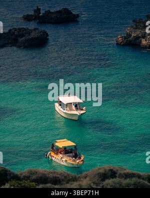 Boote ankern in türkisfarbenem Wasser in der Nähe der felsigen Kalksteinküste von Comino Island, Malta, Mittelmeer Stockfoto