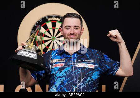 Luke Humphries feiert mit der Trophäe, nachdem er das Finale gegen Luke Litttler während der BetMGM Premier League Play-offs im O2, London gewonnen hat. Bilddatum: Donnerstag, 29. Mai 2025. Stockfoto