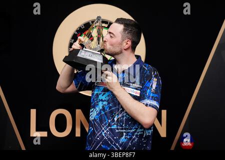 Luke Humphries feiert mit der Trophäe, nachdem er das Finale gegen Luke Litttler während der BetMGM Premier League Play-offs im O2, London gewonnen hat. Bilddatum: Donnerstag, 29. Mai 2025. Stockfoto
