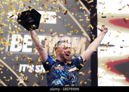 Luke Humphries feiert mit der Trophäe, nachdem er das Finale gegen Luke Litttler während der BetMGM Premier League Play-offs im O2, London gewonnen hat. Bilddatum: Donnerstag, 29. Mai 2025. Stockfoto