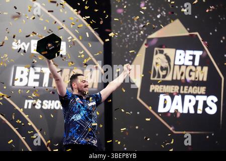 Luke Humphries feiert mit der Trophäe, nachdem er das Finale gegen Luke Litttler während der BetMGM Premier League Play-offs im O2, London gewonnen hat. Bilddatum: Donnerstag, 29. Mai 2025. Stockfoto