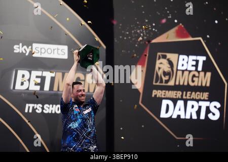 Luke Humphries feiert mit der Trophäe, nachdem er das Finale gegen Luke Litttler während der BetMGM Premier League Play-offs im O2, London gewonnen hat. Bilddatum: Donnerstag, 29. Mai 2025. Stockfoto