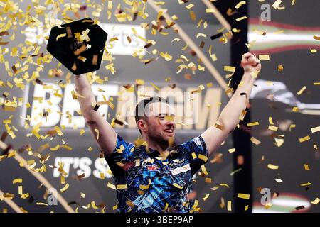 Luke Humphries feiert mit der Trophäe, nachdem er das Finale gegen Luke Litttler während der BetMGM Premier League Play-offs im O2, London gewonnen hat. Bilddatum: Donnerstag, 29. Mai 2025. Stockfoto