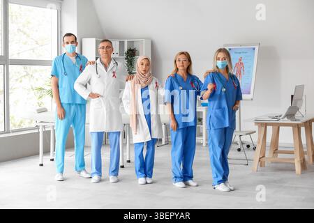 Das professionelle Ärzteteam mit roten Bändern in der Klinik. Konzept des Welt-AIDS-Tages Stockfoto