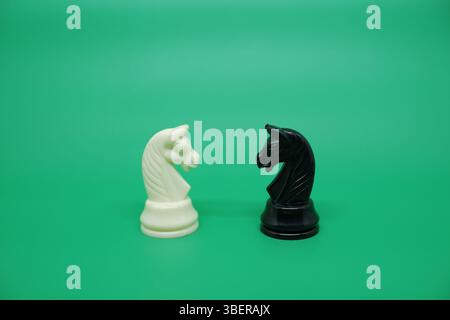 Zwei Pferde- oder Ritterschachfiguren, schwarz und weiß zueinander. Im Schachspiel haben Pferde eine einzigartige und tödliche Bewegung, nämlich den L-Zug. Stockfoto