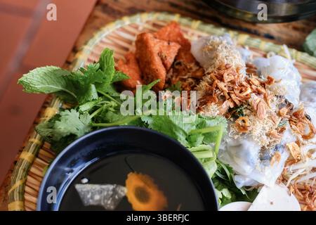 Banh Cuon nach Hanoi-Art, Reisnudelrollen mit gemahlenem Schweinefleisch, serviert mit Cha lua (Wurst), frischen Kräutern und nuoc cham Dipping Sauce im VN Street Foods Stockfoto