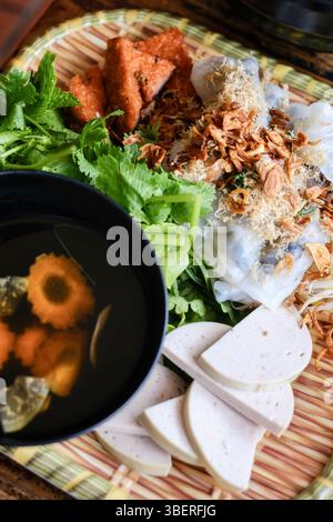Banh Cuon nach Hanoi-Art, Reisnudelrollen mit gemahlenem Schweinefleisch, serviert mit Cha lua (Wurst), frischen Kräutern und nuoc cham Dipping Sauce im VN Street Foods Stockfoto