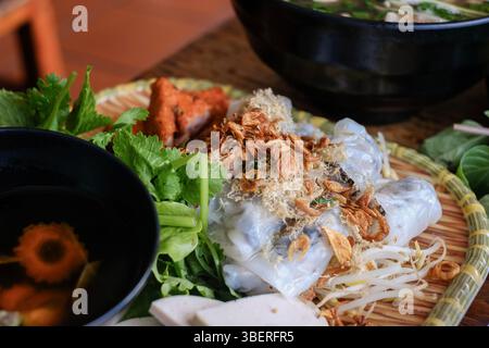 Banh Cuon nach Hanoi-Art, Reisnudelrollen mit gemahlenem Schweinefleisch, serviert mit Cha lua (Wurst), frischen Kräutern und nuoc cham Dipping Sauce im VN Street Foods Stockfoto