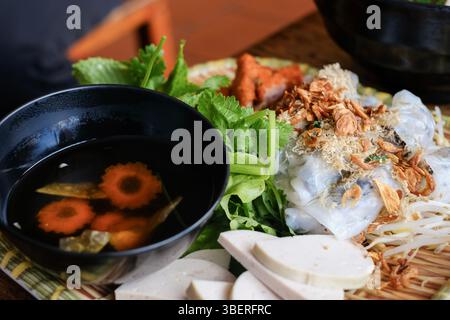 Banh Cuon nach Hanoi-Art, Reisnudelrollen mit gemahlenem Schweinefleisch, serviert mit Cha lua (Wurst), frischen Kräutern und nuoc cham Dipping Sauce im VN Street Foods Stockfoto