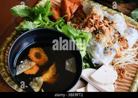 Banh Cuon nach Hanoi-Art, Reisnudelrollen mit gemahlenem Schweinefleisch, serviert mit Cha lua (Wurst), frischen Kräutern und nuoc cham Dipping Sauce im VN Street Foods Stockfoto