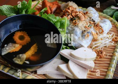 Banh Cuon nach Hanoi-Art, Reisnudelrollen mit gemahlenem Schweinefleisch, serviert mit Cha lua (Wurst), frischen Kräutern und nuoc cham Dipping Sauce im VN Street Foods Stockfoto