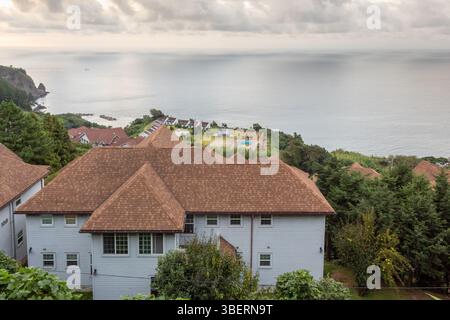 Weißes Haus entlang der Berge und Klippen des Küstenwassermeeres der Insel Ulleungdo in Südkorea während des Sonnenaufgangs Stockfoto