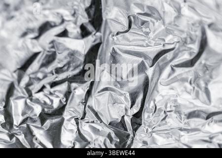 Zerknitterte silberfarbene Folienoberfläche mit komplizierter Textur und reflektierenden Eigenschaften. Ideal für Hintergründe, Muster oder abstrakte Designs Stockfoto
