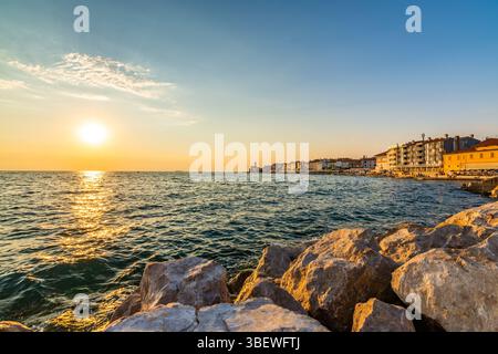 Sonnenuntergang über der adria in Piran, Slowenien. Alte antike und mittelalterliche Stadt, Blick von der Küste und vom Hafen. Alte Steine im Vordergrund, schön Stockfoto