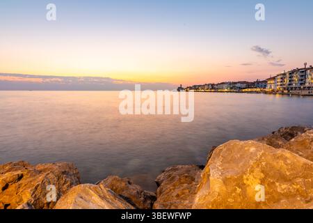 Sonnenuntergang über der adria in Piran, Slowenien. Alte antike und mittelalterliche Stadt, Blick von der Küste und vom Hafen. Alte Steine im Vordergrund, schön Stockfoto