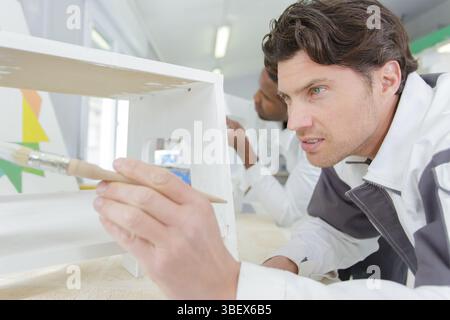Ein Mann malt ein Möbel Stockfoto