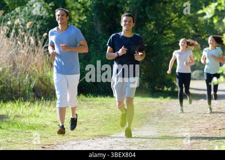 Zwei Männer und zwei Frauen joggen durch den Park Stockfoto