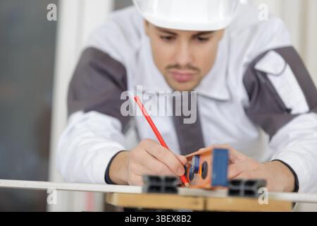 Handwerker-Messung ein Brett aus Holz mit einer Wasserwaage Stockfoto