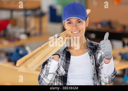 Junge konzentrierte Zimmermannin mit Holzdielen Stockfoto
