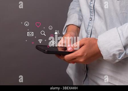 Eine junge Frau, die Social-Media-Anwendungen mit einem Smartphone öffnet. Online-Dating, chatten mit Freunden und senden Emotionssymbole. Stockfoto