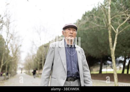 Älterer Mann, der im Winter Musik hört und im Park spaziert Stockfoto