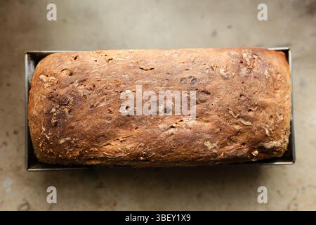 Vollkornbrot im rustikalen Stil perfekt auf einem Holzschneidebrett platziert. Brotlaib zu Hause gebacken. Hausgemachte Backwaren. Gesunde Ernährung Stockfoto