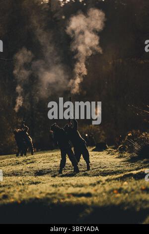 Ein vertikales Foto von Silhouetten von Waffen, die mit Gewehrrauch bei einem Fasanenschießen in Großbritannien schießen Stockfoto
