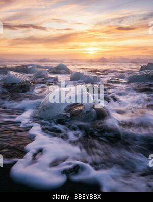 Gletschereis am Diamond Beach bei Sonnenaufgang mit abstürzenden Wellen, in der Nähe von Jokulsarlon, Süd-Island, Island, Polarregionen Stockfoto