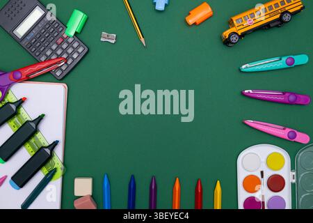Blick von oben auf farbenfrohe Schulmaterialien, einschließlich Buntstifte, Scheren, Marker, einen Spielzeugschulbus, Aquarellfarben und einen Taschenrechner Stockfoto