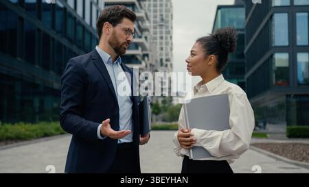 Zwei multirassische Geschäftsleute treffen sich in der Stadt und schütteln formell die Hände und reden afroamerikanische Geschäftsfrau mit Frau Stockfoto