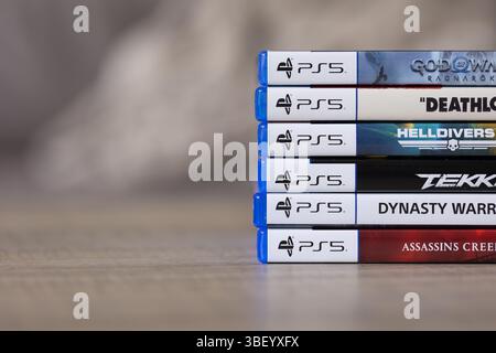 Brecht, Belgien - 18. april 2025: Ein Stapel von sony playstation 5-Videospielhüllen oder -Boxen auf einem Holztisch. Die Anzahl der PS5-Spiele ist vielfältig Stockfoto