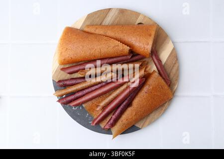 Köstliche Fruchtlederrollen auf weiß gekachelten Tisch, Blick von oben Stockfoto