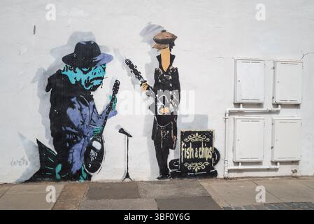 Fish and Chips, Graffiti von Fischen, die in einer Band spielen, in Hüten und Mänteln gekleidet Stockfoto