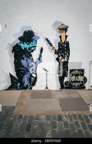 Fish and Chips, Graffiti von Fischen, die in einer Band spielen, in Hüten und Mänteln gekleidet Stockfoto