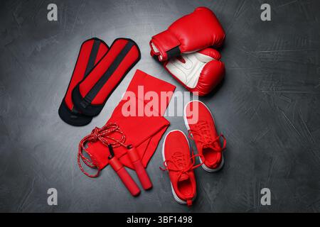 Sportbekleidung, Turnschuhe, Boxhandschuhe, Seilspringen und Knöchelgewichte auf grauem Hintergrund, flach Stockfoto