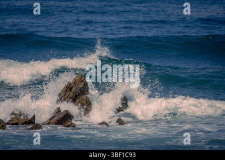 Mächtige Wellen krachen entlang der südafrikanischen Küste gegen zerklüftete Felsen, die in lebendigen Farben und Details erfasst werden. Stockfoto