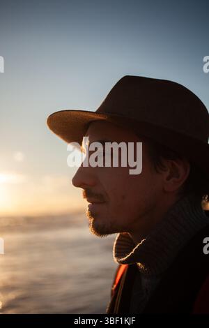 Der Mann spaziert am Sandstrand entlang, gebadet in warmen Sonnenuntergang Stockfoto