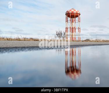 Wasserturm reflektiert in Pfütze an der Straße Stockfoto