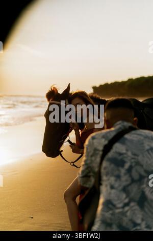 Der Fotograf fotografiert eine Frau mit einem Pferd am Strand Stockfoto