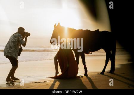 Der Fotograf fotografiert eine Frau mit einem Pferd am Strand Stockfoto