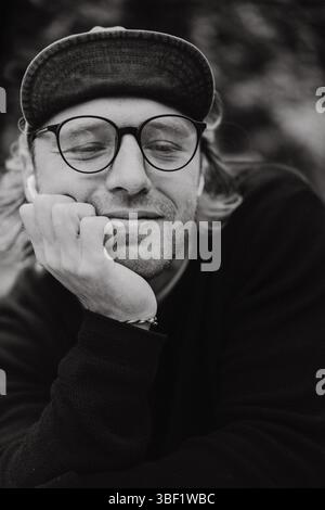 Nahporträt eines Mannes in Brille und Kappe, schwarz-weiß Stockfoto