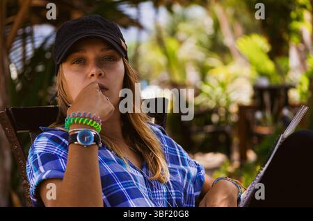 Entspannte junge Frau in tropischem Ambiente mit Notizbuch Stockfoto